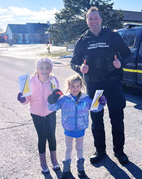 Les sœurs Audrey et Maelle Servais (gauche et centre) ont reçu des contraventions positives et des cartes-cadeaux valable dans le commerce local de leur choix des mains de Jonathan Guindon (droite), agents de la Sécurité publique et de la règlementation. (Municipalité de Russell)