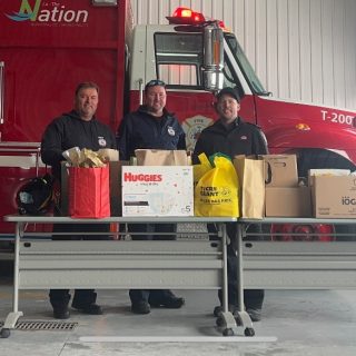 Members of the Nation Fire Department stand alongside donations collected during the annual St. Bernardin food drive, which raised $1,355 for the Riceville Food Bank thanks to strong community support and a contribution from the St. Bernardin Firefighters Association.