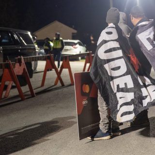 Des manifestants, beaucoup moins nombreux que la Police provinciale de l'Ontario, se tiennent le long du chemin Saint-Pascal-Baylon avec des pancartes dénonçant l'événement de drague et le premier ministre Justin Trudeau.