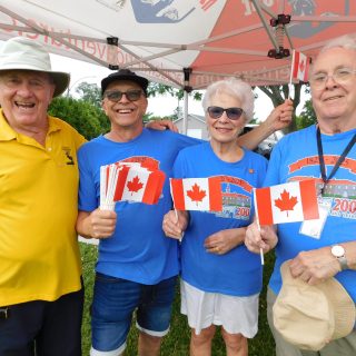 Jean-François Bédard (à gauche), Robert Prévost, Louise Bédard et Dale Garvin du Patrimoine L'Orignal-Longueuil Héritage distribuent des drapeaux de la feuille d'érable à tous les participants à la fête du Canada.