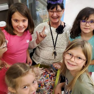 Fête d’Halloween organisée et animée par la directrice adjointe de la bibliothèque de Casselman, Madame Christine Lepage, entourée des jeunes enfants s’amusant lors de différentes activités d’Halloween.
