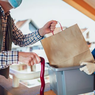 Teenage girl is delivering some groceries to an elderly person. Contactless delivery during the quarantine